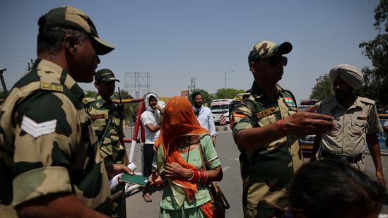 A military personnel with border security force checks passport of pakistani citizens as they prepare to leave india, at the attari wagah border crossing near amritsar